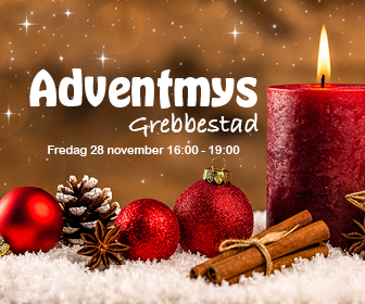 adventmys i Grebbestad ett brinnande ljus som står i snö med julpynt vid sin sida